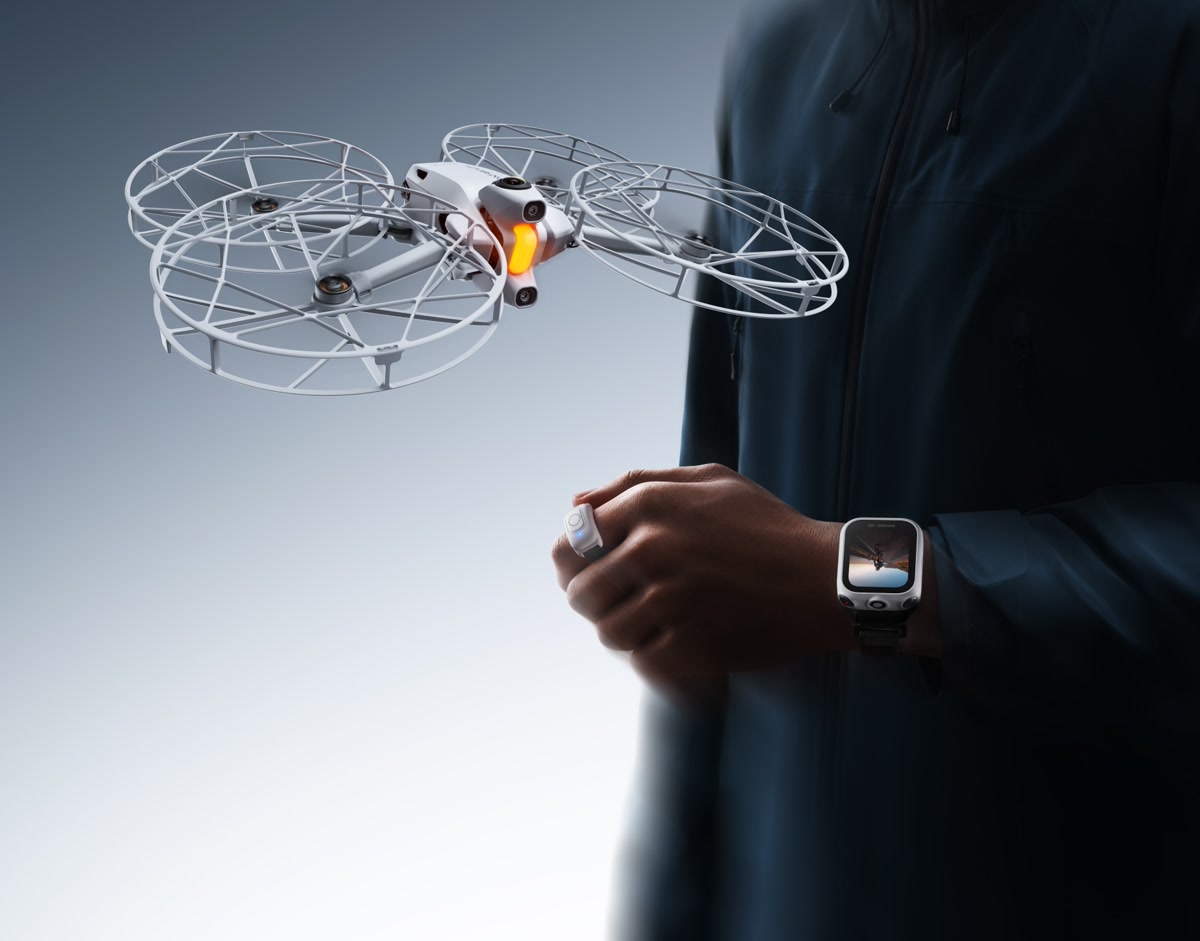 The Antigravity A1 drone hovers beside a person wearing the Watch Remote and Ring Remote