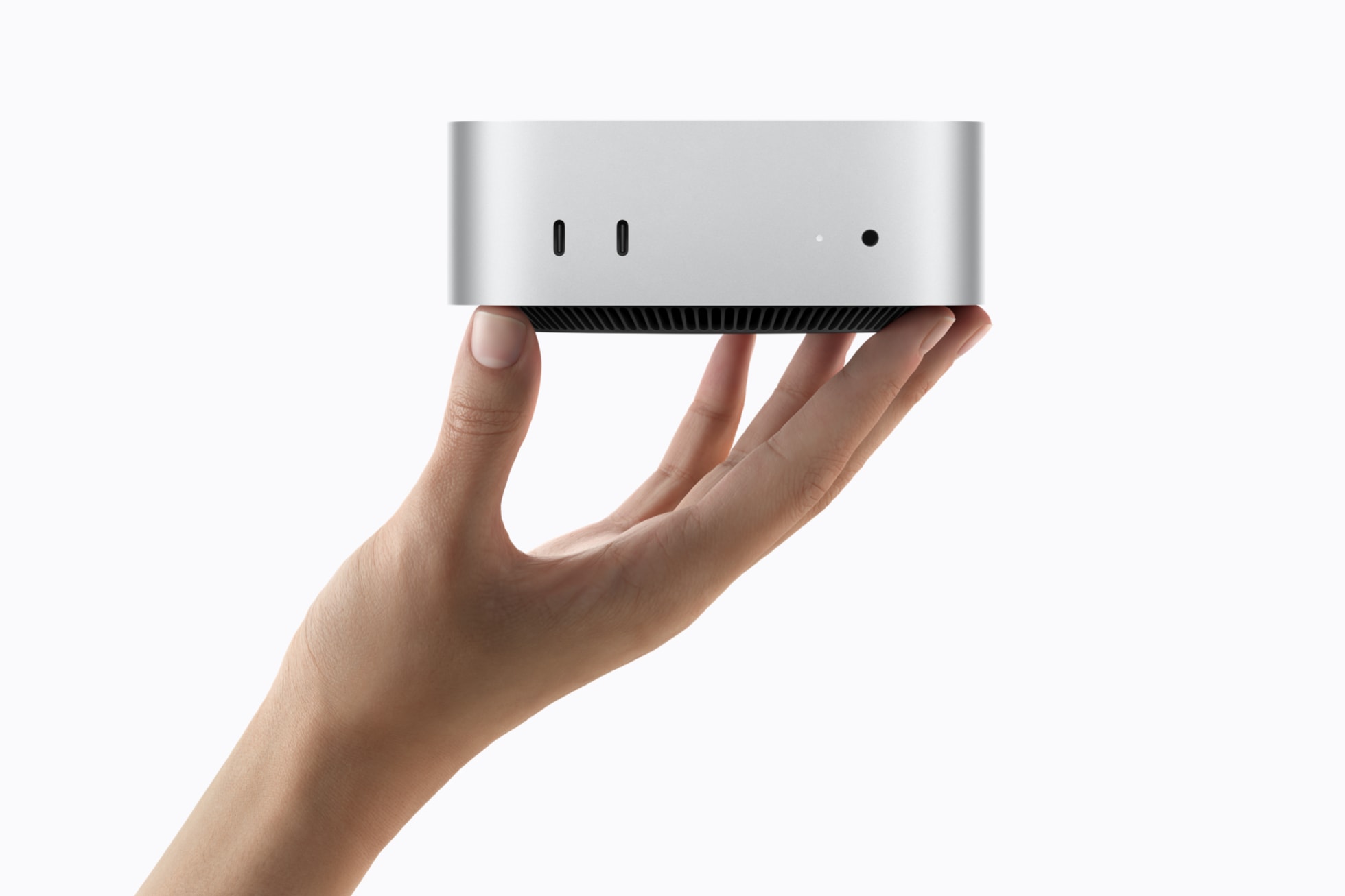 A hand holds the compact silver Mac mini with its Apple logo facing up