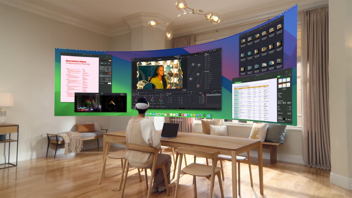 A person wearing Apple Vision Pro works across the larger curved Mac Virtual Display previewed for visionOS 2