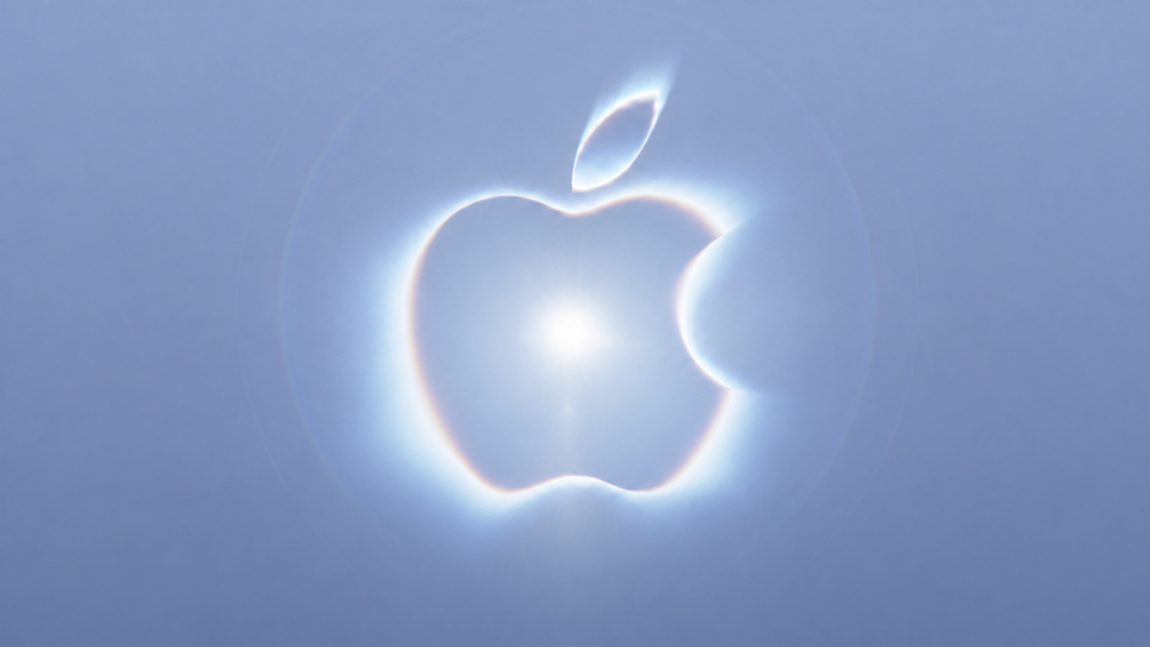 A glowing pale blue Apple logo from the Surprise and shine event invitation
