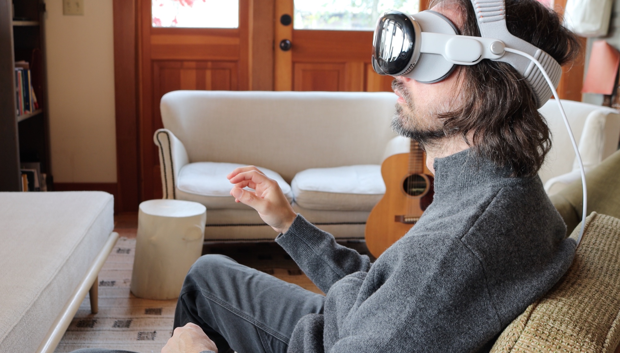 Gregory Wieber wearing an Apple Vision Pro and making a hand gesture while seated at home