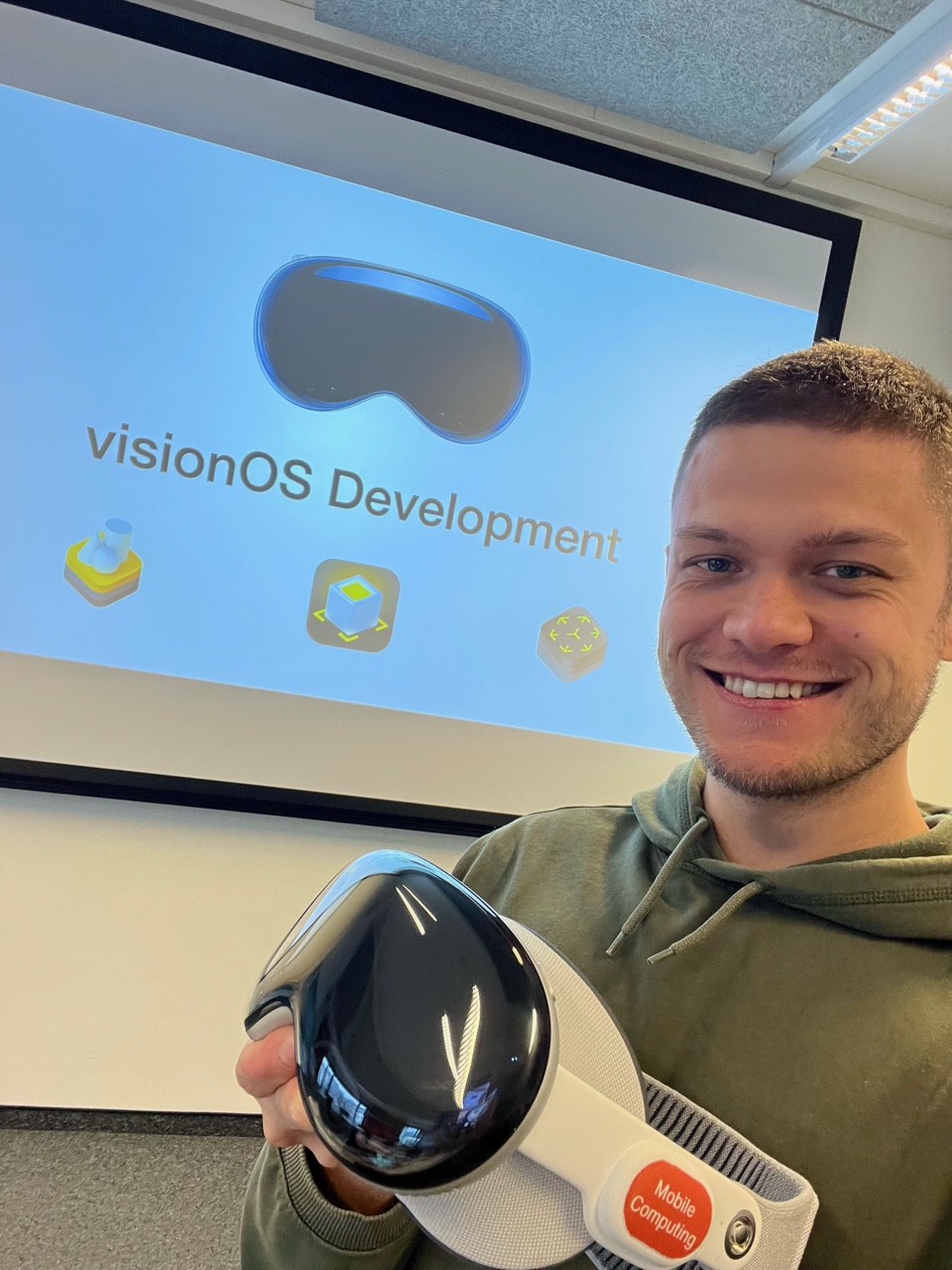 Michael Temper holding an Apple Vision Pro in front of a visionOS development presentation