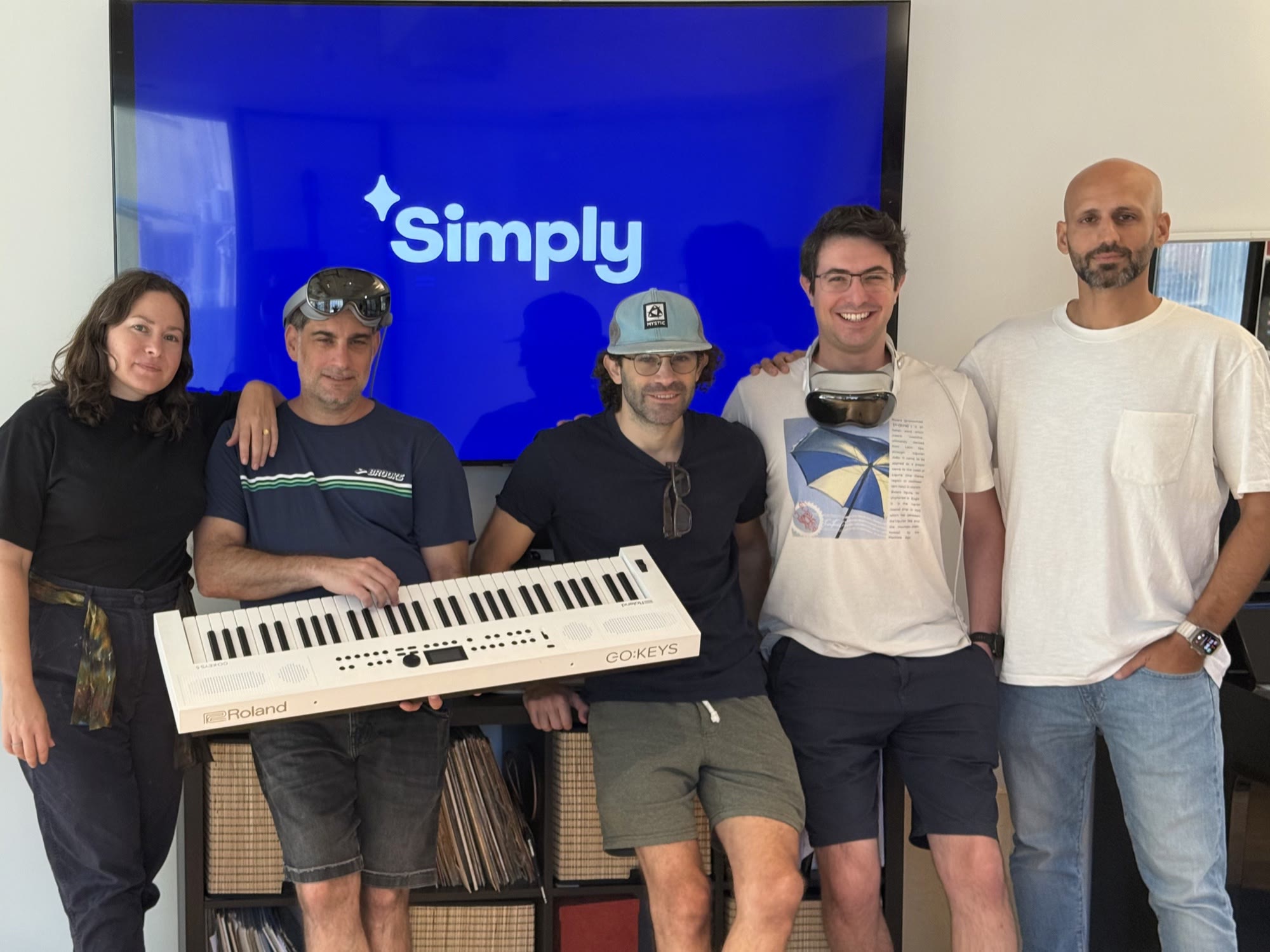 Simply XR team members Danielle Zilberberg, Omer Wodnizki, Tal Ron, Gil Peled, and Eliran Douenias gathered around a piano keyboard with Apple Vision Pro headsets