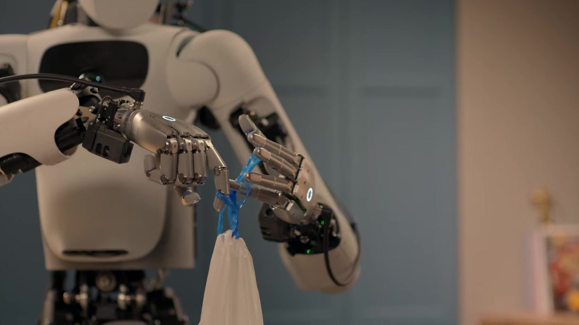 An Apollo humanoid uses two five-fingered robotic hands to tie a blue trash bag