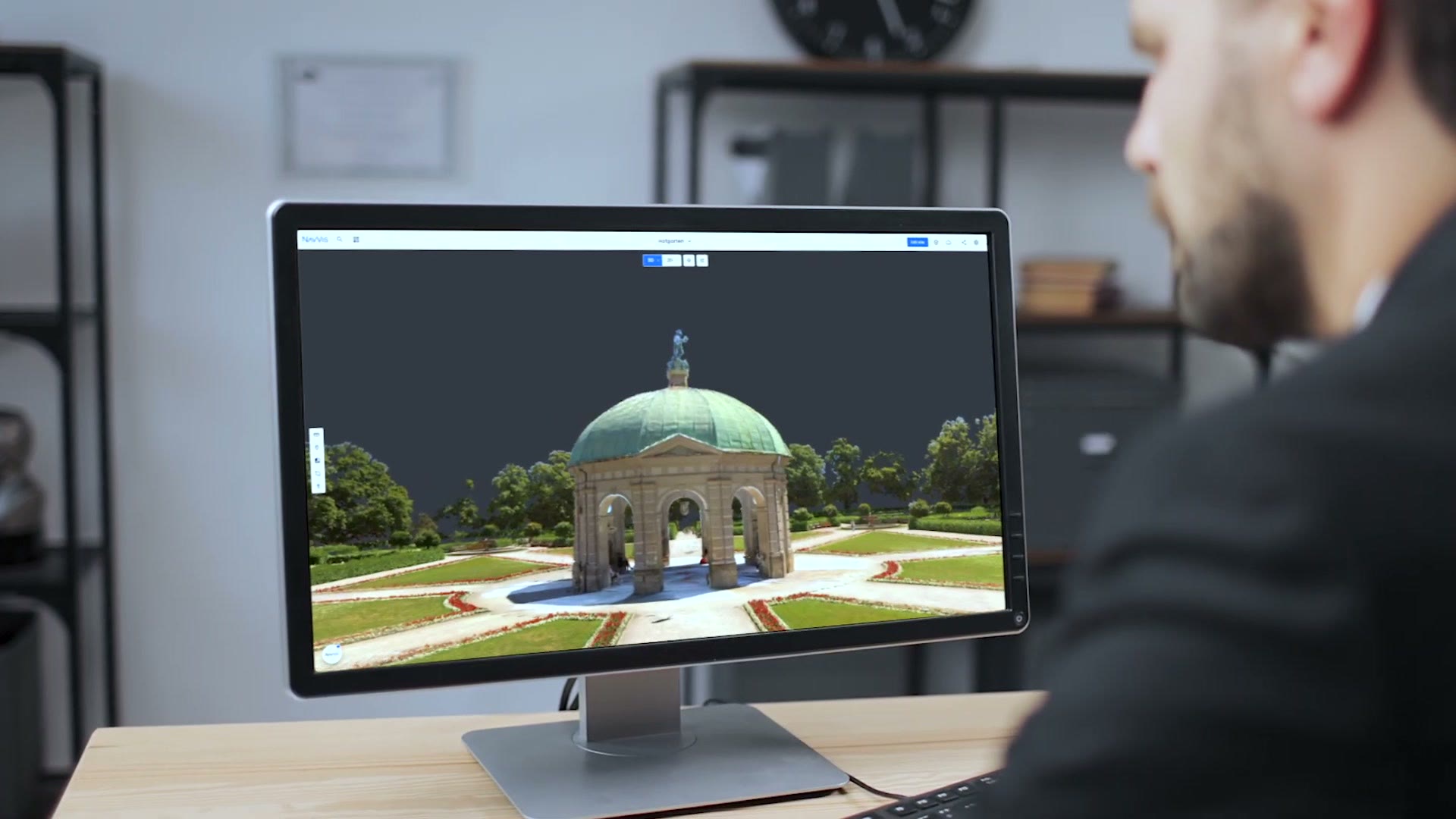 A person views a Gaussian splat of Munich's Hofgarten in NavVis IVION on a desktop monitor