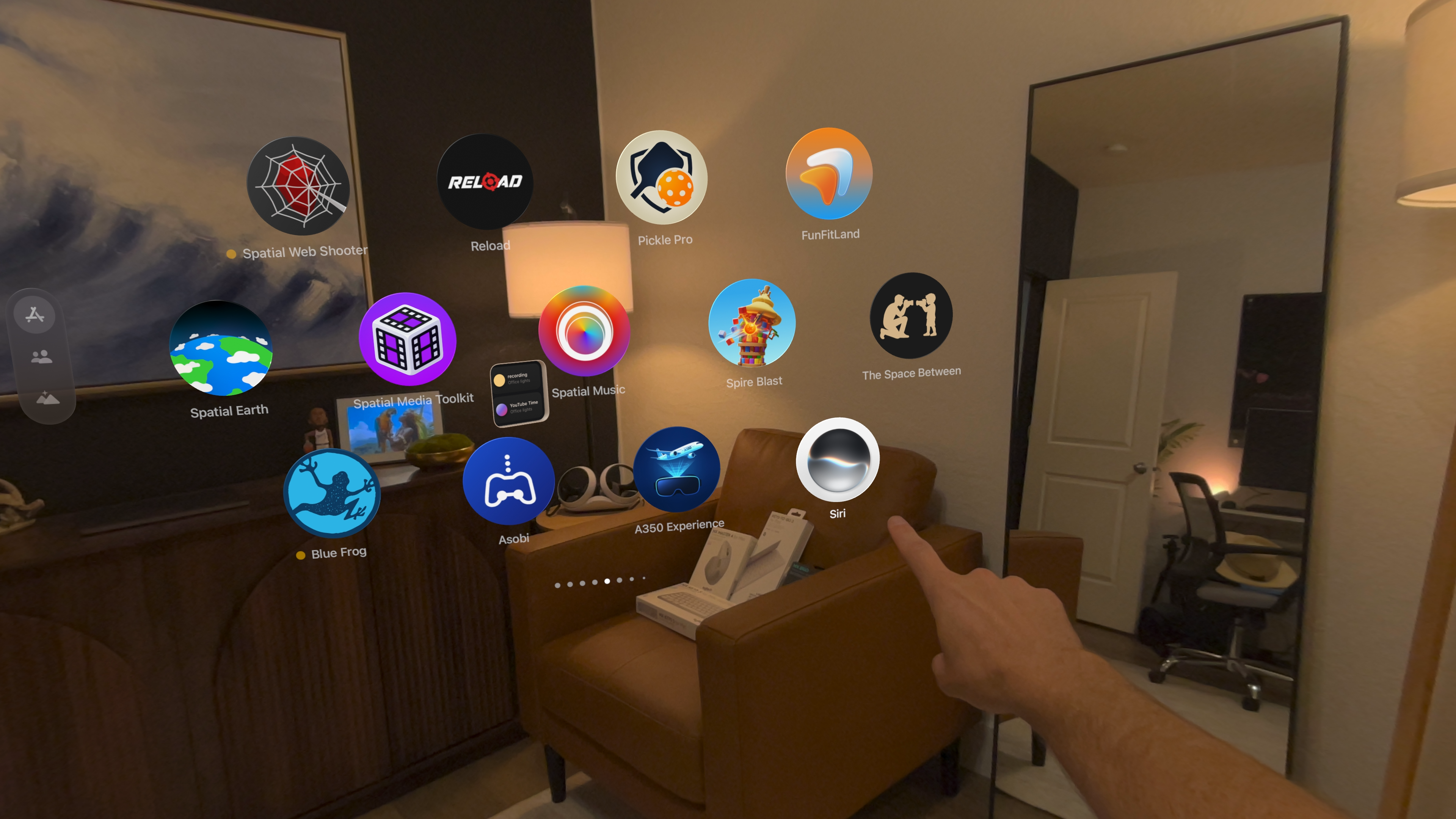 A hand pointing toward the new circular Siri app icon in Apple Vision Pro Home View